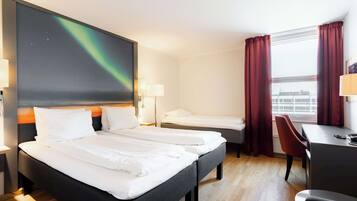 Una habitación de hotel con una cama grande, una cama más pequeña, un escritorio y una silla.