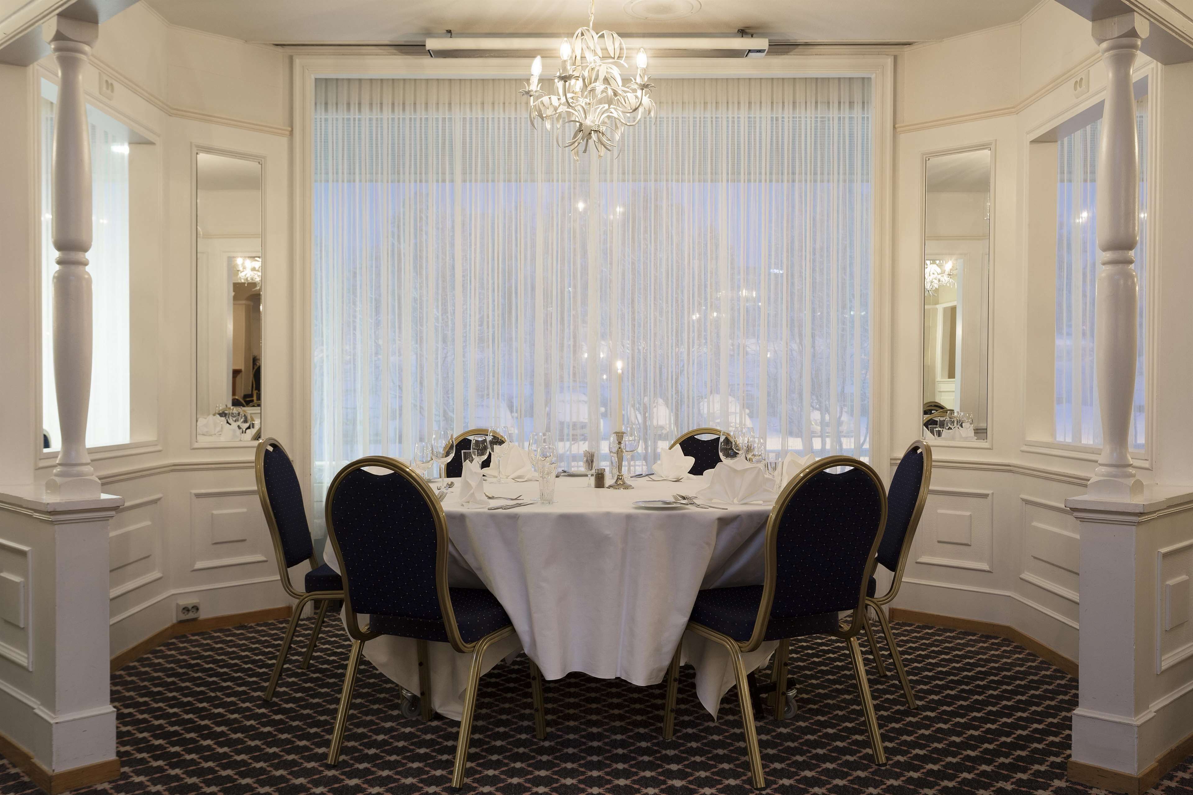 A formal dining room with a chandelier, white tablecloth, and four chairs.