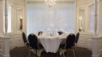 A formal dining room with a chandelier, white tablecloth, and four chairs.