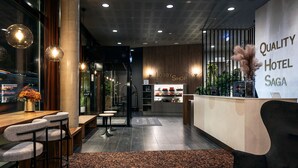 A modern hotel lobby with a reception desk, bar area, and a lobby shop. - Quality Hotel Saga (Tromsø)