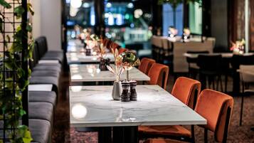 Un restaurant avec de longues tables, des sièges confortables et une vue sur la ville.