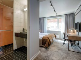 Una habitación de hotel con baño, cama, escritorio y televisor.