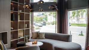 A modern living room with a curved sofa, a round coffee table, and a bookshelf. - Quality Hotel Saga (Tromsø)