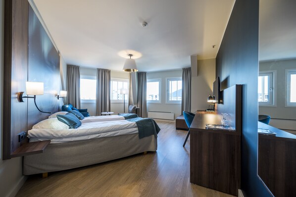 A modern hotel room with a large bed, a desk, and a TV. There are curtains, a ceiling fan, and a window with a view. - Quality Hotel Saga (Tromsø)