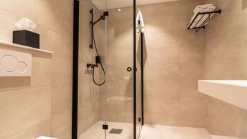 A modern bathroom with a glass-enclosed shower, a white sink, and a towel rack.
