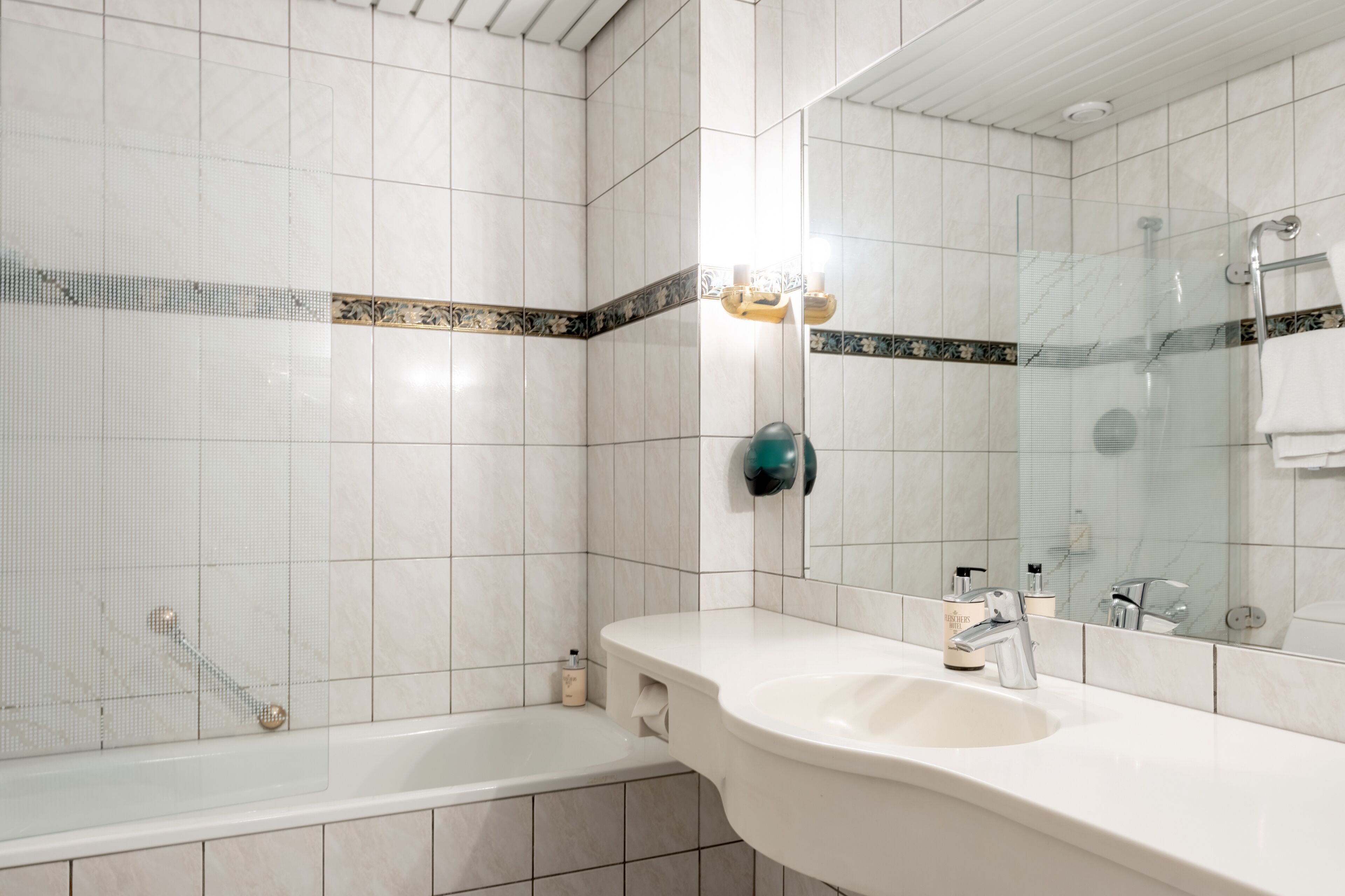 Un baño moderno con lavamanos blanco, espejo y bañera.