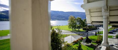 A view from a window overlooking a lake, a small building, and a parking area.