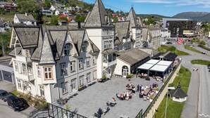 A hotel with a large outdoor patio area, multiple dining tables, and a covered seating area. - Fleischer's Hotel (Voss)