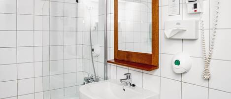 A modern bathroom with a glass shower enclosure, a white sink, and a wooden-framed mirror.