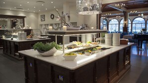 A buffet setup with various food items, a decorative centerpiece, and a chandelier. - Fleischer's Hotel (Voss)