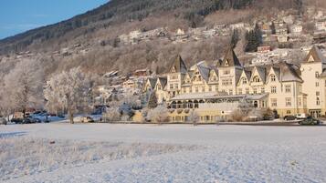 Paisaje nevado con una hilera de edificios tradicionales, con tejados pronunciados y un edificio central con una amplia entrada en arco.