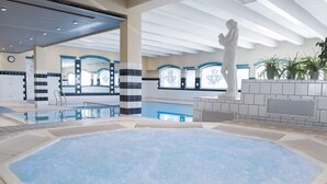 A large indoor swimming pool with a hot tub, surrounded by tiled walls and a statue. - Fleischer's Hotel (Voss)