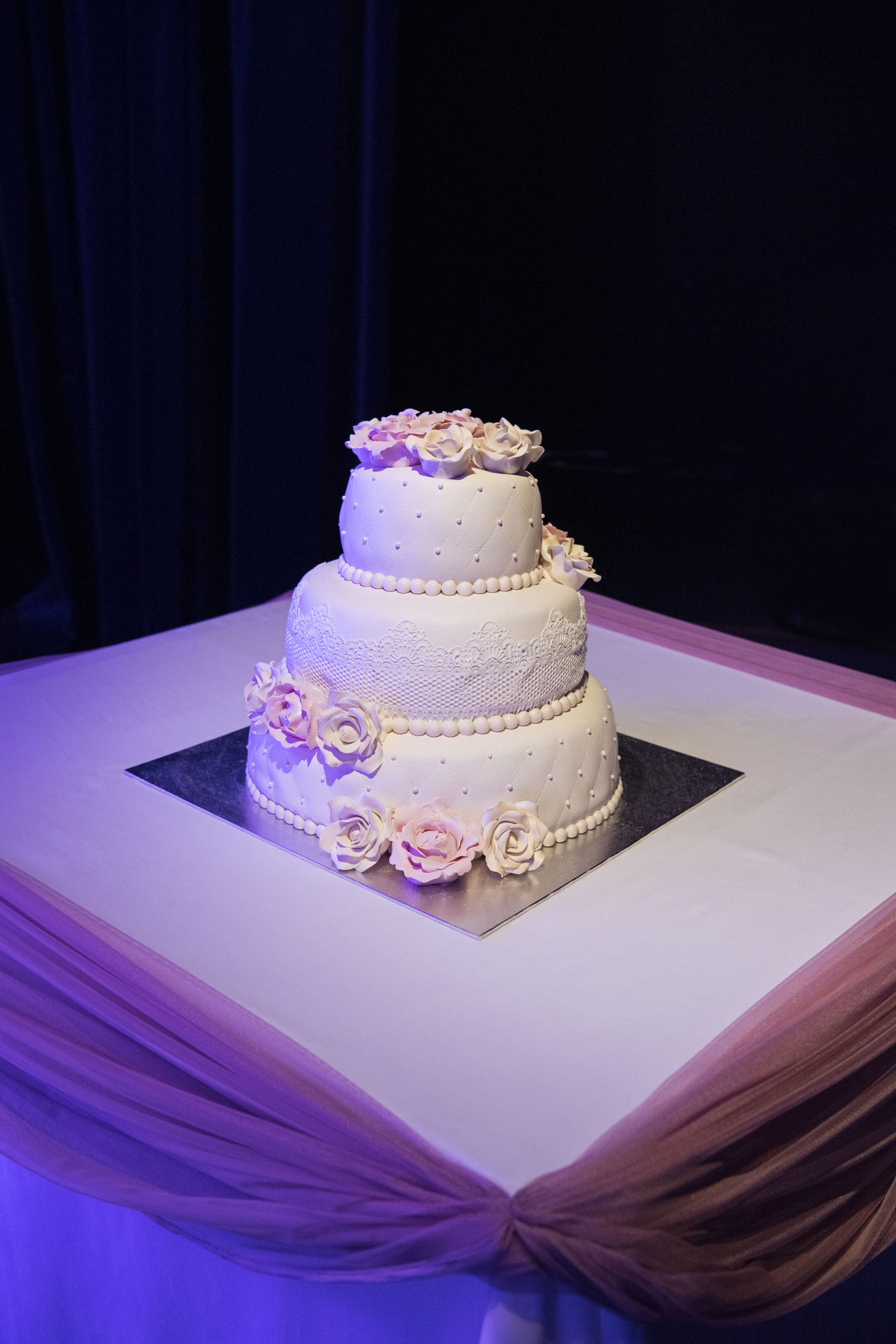 Ein mehrstöckiger Kuchen mit floralen Verzierungen auf einem quadratischen Tisch.