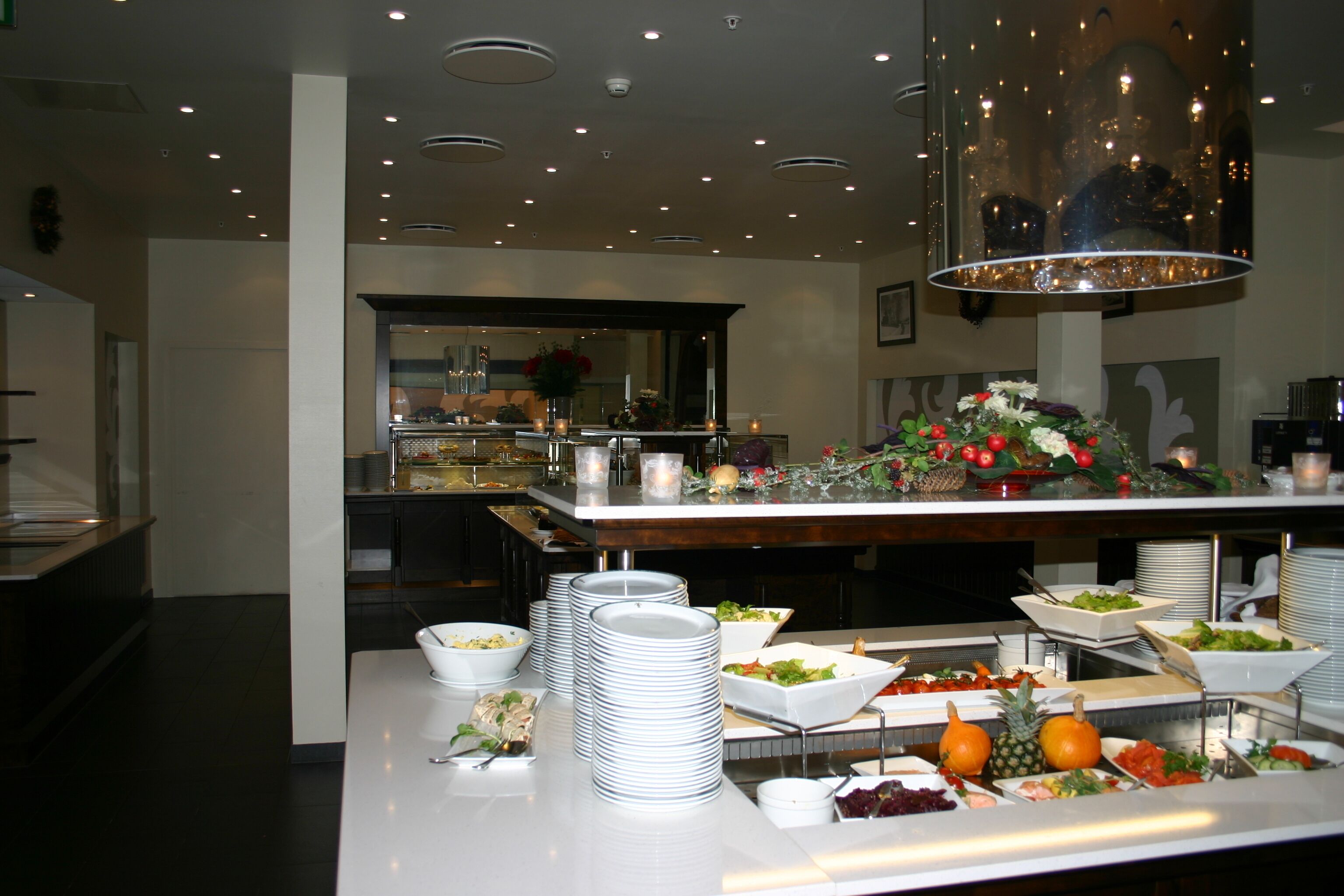 Disposição de buffet com diversos alimentos e um espelho refletindo o ambiente.