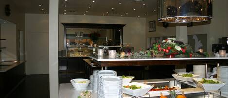 Disposição de buffet com diversos alimentos e um espelho refletindo o ambiente.