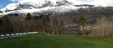 A golf course with a mountain backdrop.