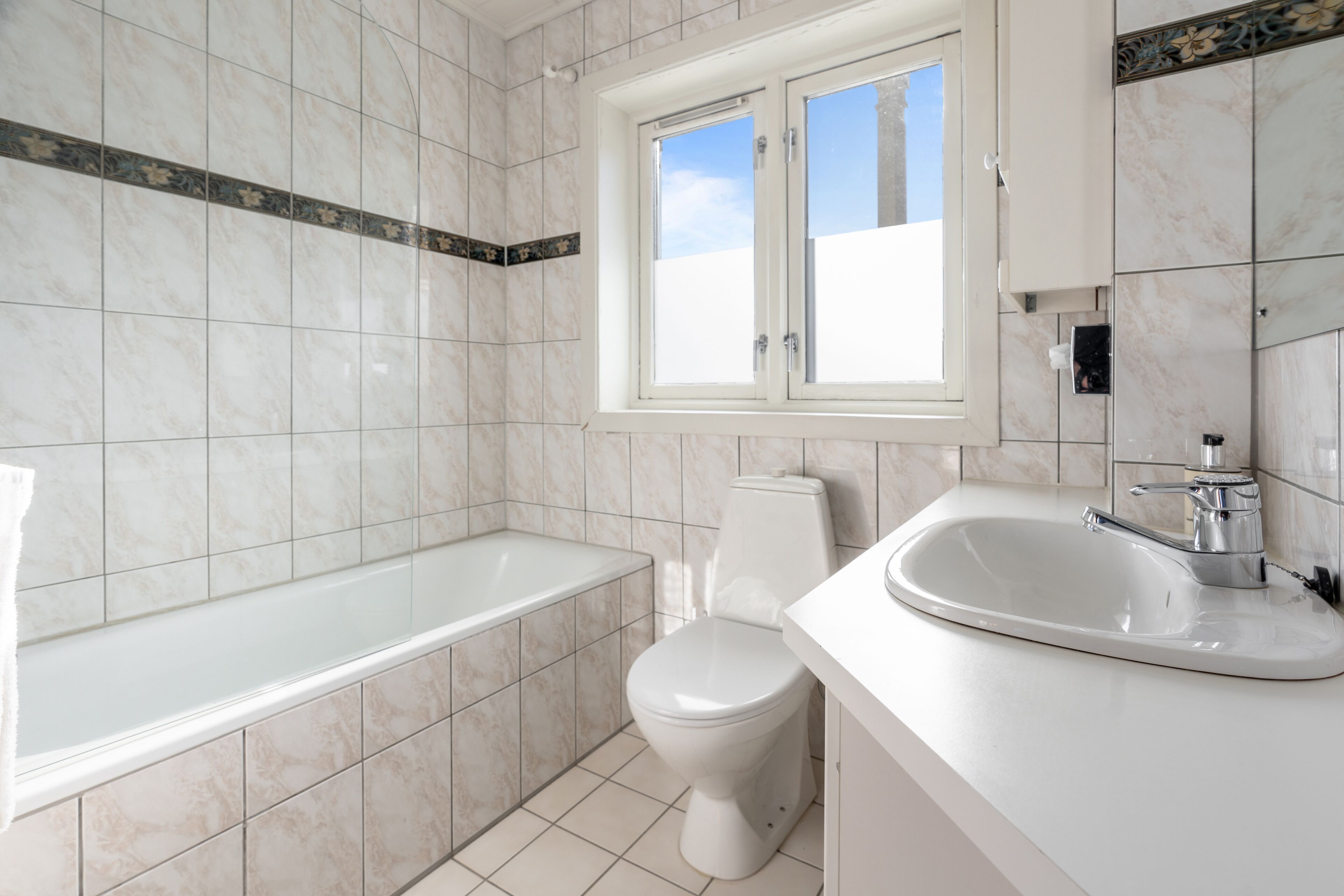 Egy modern fürőszoba, amelyben kád, WC és mosdókagyló található.