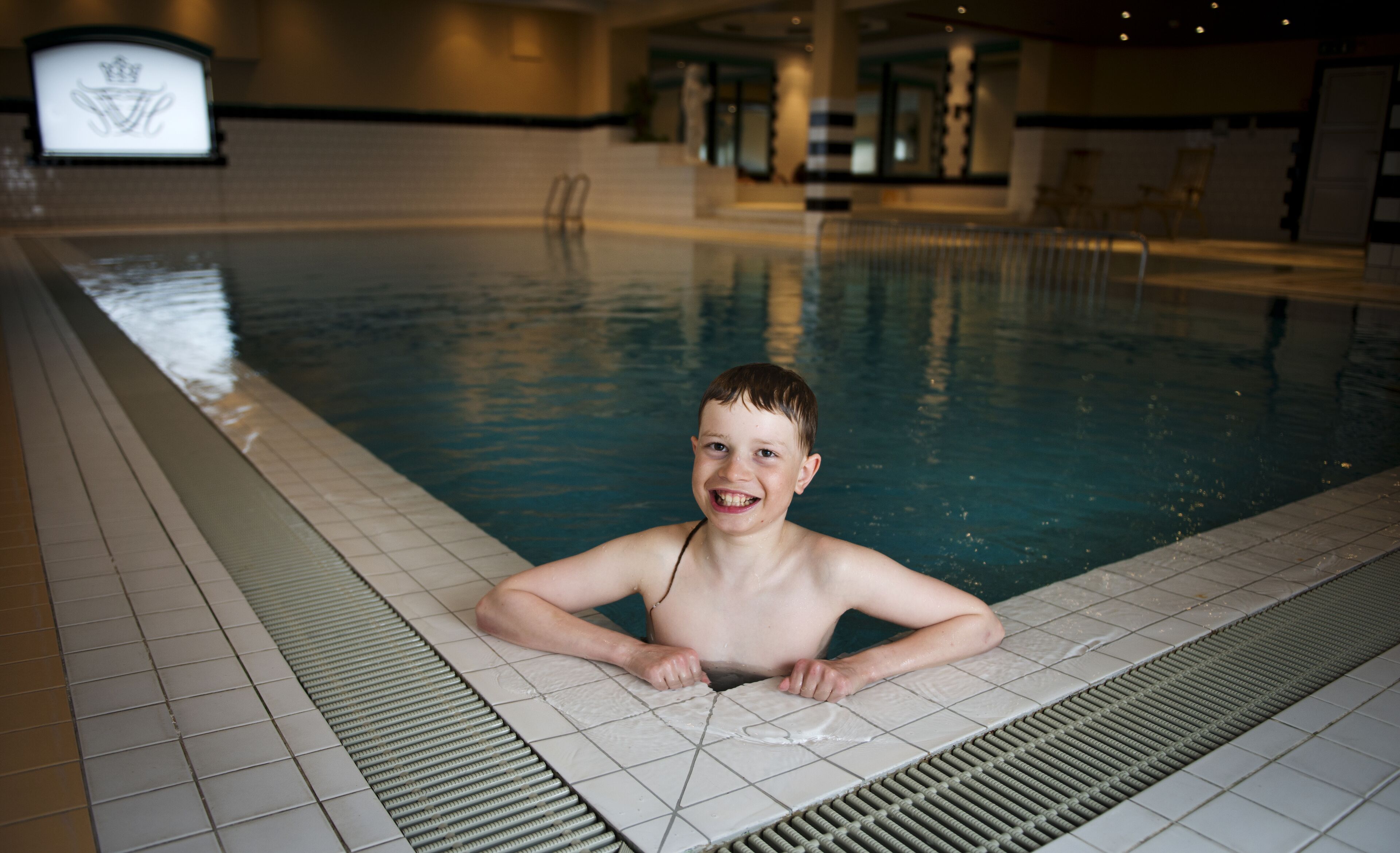 A swimming pool with tiled edges and a drain system.