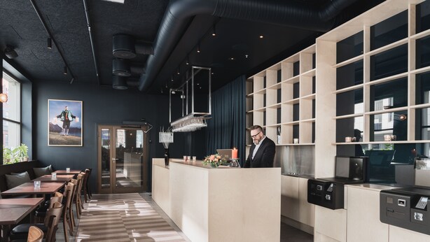 Un moderno vestíbulo de hotel con una recepción, zona de estar y un amplio ventanal.