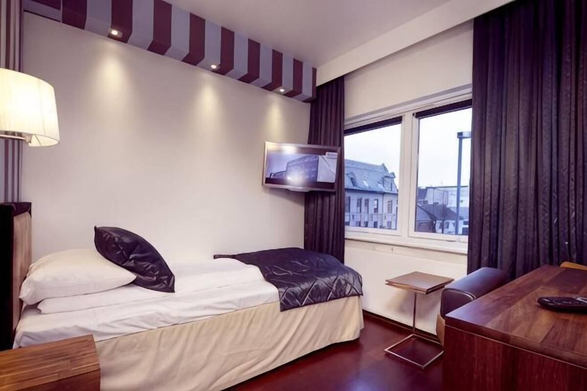 Una habitación de hotel con cama, televisión, ventana con vistas y escritorio.