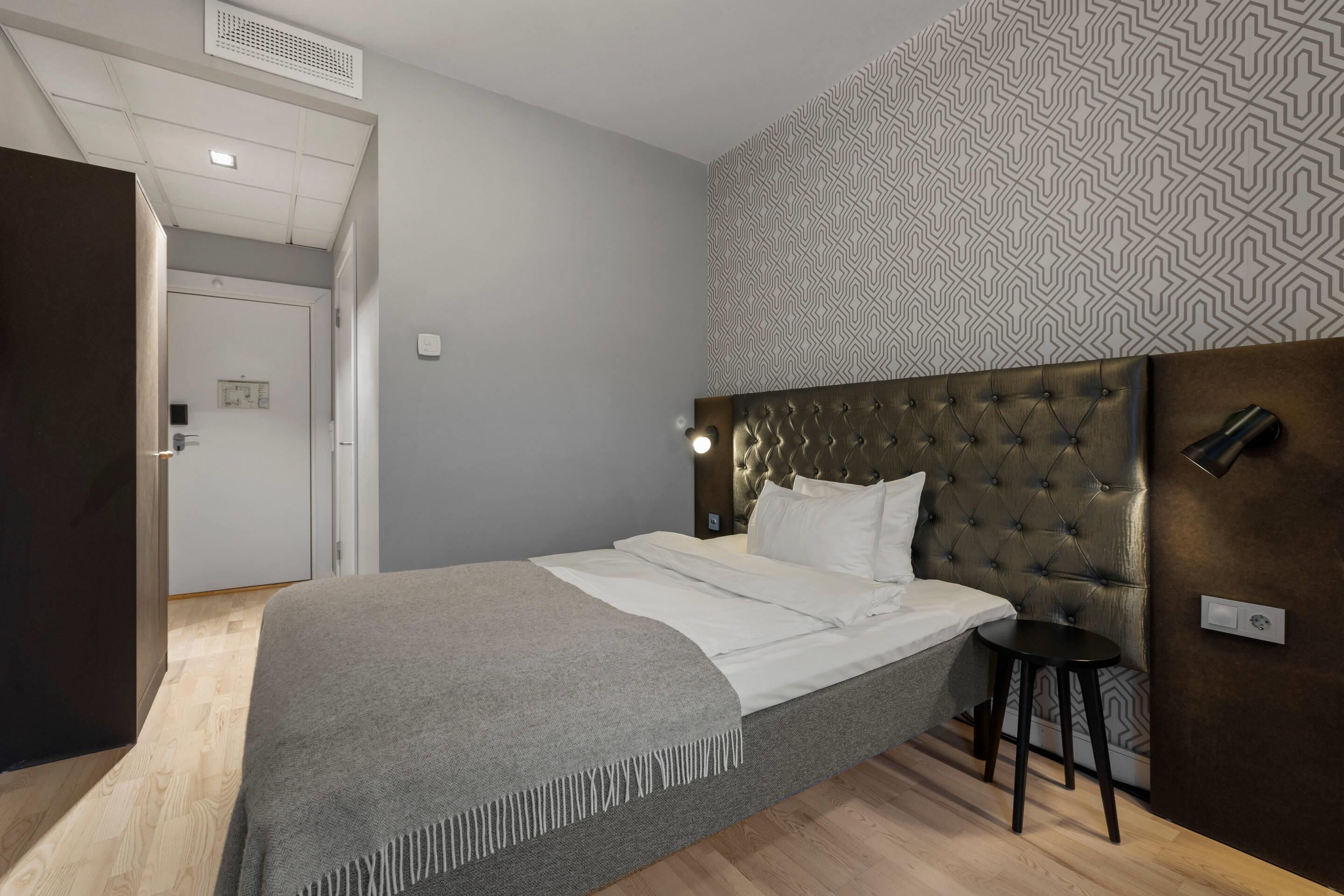 Ein modernes Schlafzimmer mit einer gepolsterten Kopfteil, einem Nachttisch und einer Wand mit Muster.