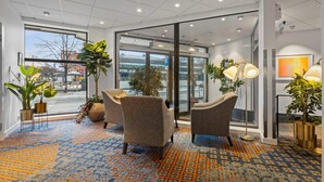 Een moderne lobby met een patroonrijk tapijt, comfortabele zithoek en grote ramen met uitzicht op de straat.