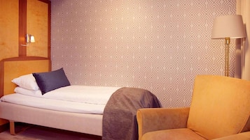Un dormitorio ordenado con una cama, una silla y una lámpara.
