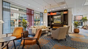 Een moderne hotellobby met een zithoek, grote ramen en een open haard.