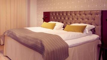 A neatly made bed with a striped throw, a tufted headboard, and patterned wall decor.