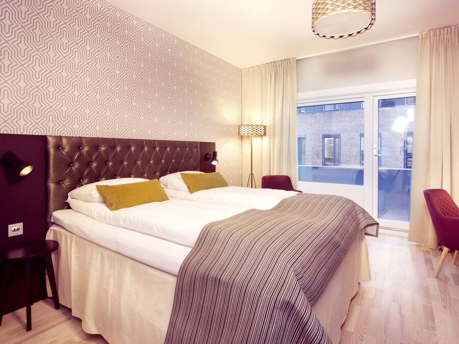 Una habitación de hotel moderna con una cama grande, un escritorio y vistas a la ciudad.