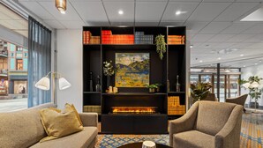 Een moderne zithoek met een open haard, comfortabele zitplaatsen en een boekenkast.