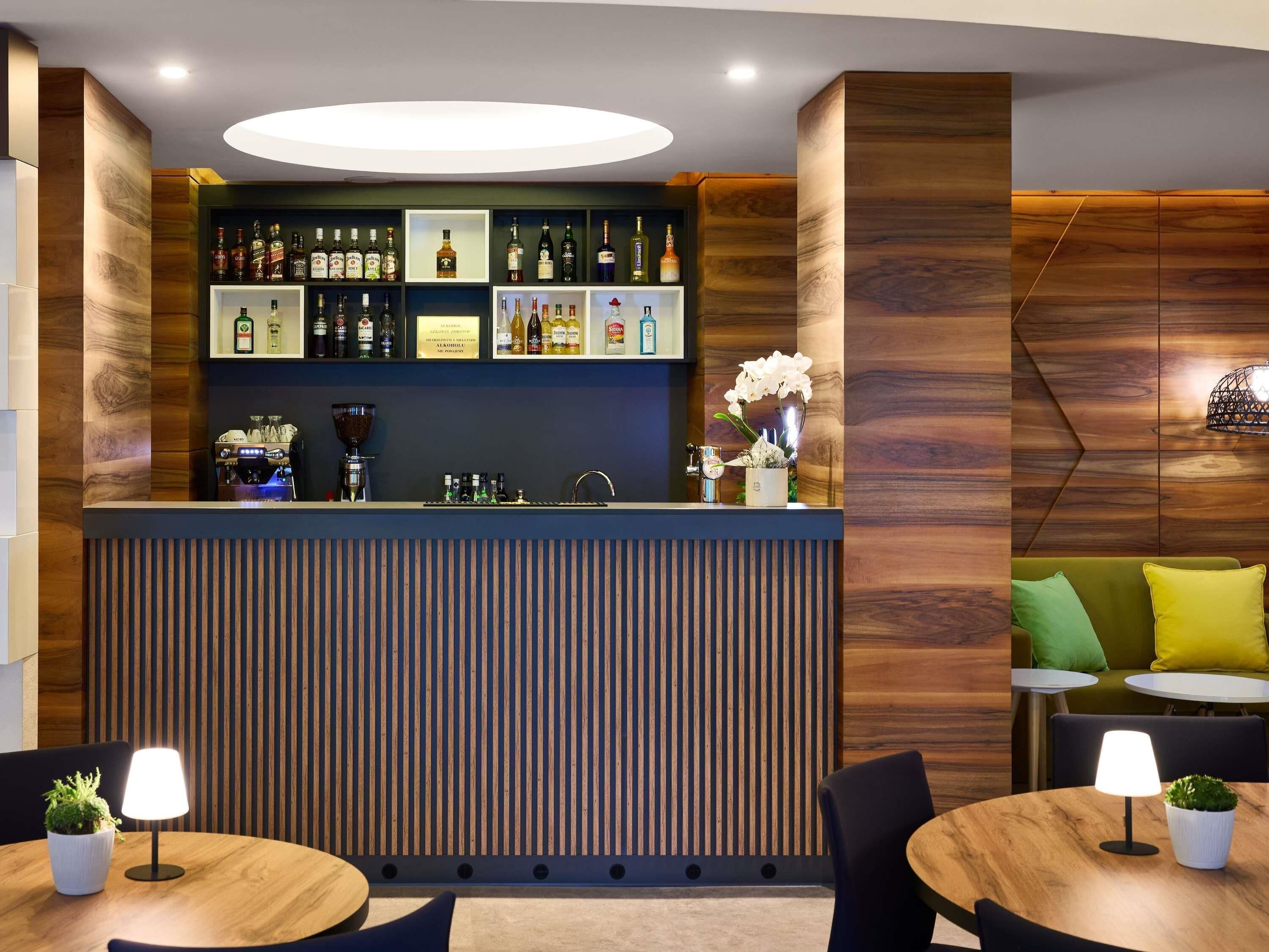 A bar area with a coffee machine, shelves of liquor bottles, and a potted orchid.