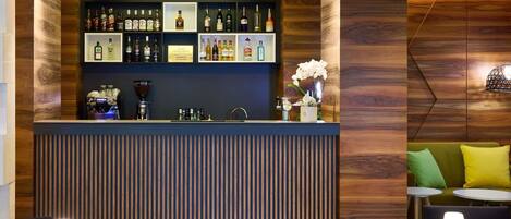 A bar area with a coffee machine, shelves of liquor bottles, and a potted orchid.