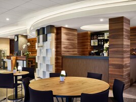Un moderno vestíbulo de hotel con una recepción, zona de estar y un bar.