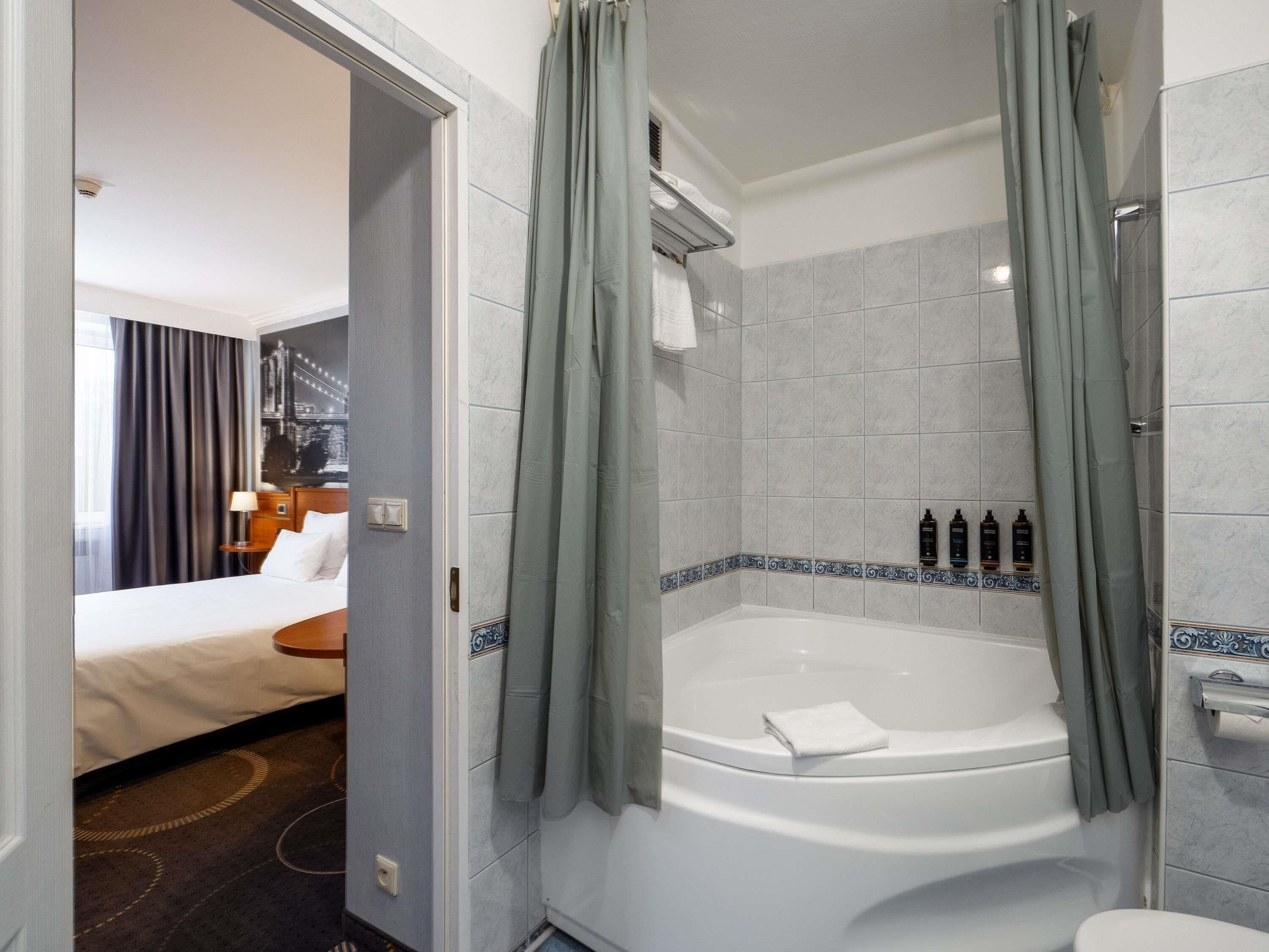 Een hotelkamer met een bed, een badkamer met een bad en een douchegordijn.