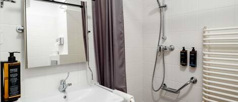A modern bathroom with a white sink, a mirror, a shower with a handheld showerhead, and a towel rack.