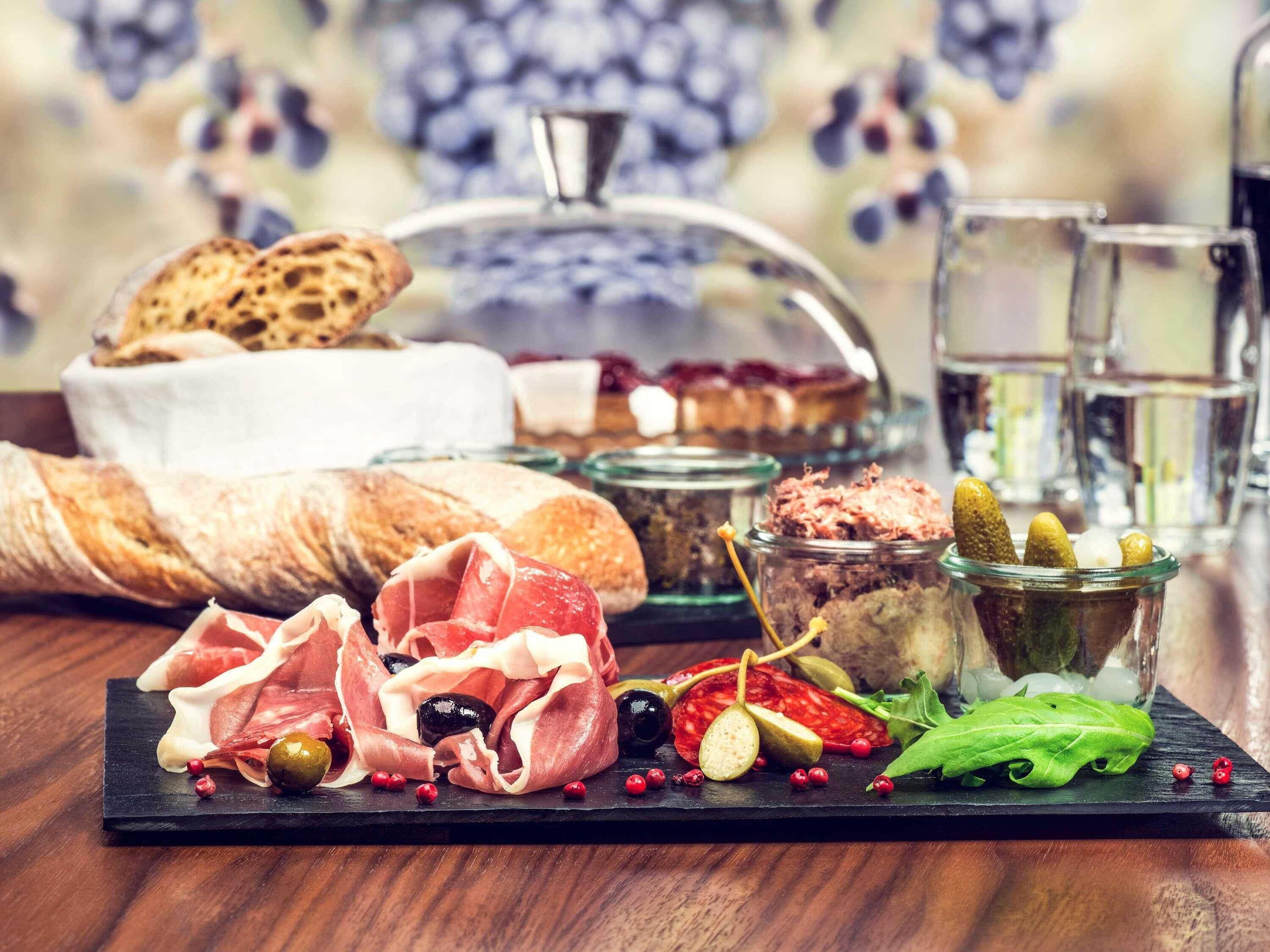 A charcuterie board with various meats, olives, and pickles.