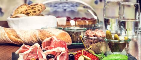 A charcuterie board with various meats, olives, and pickles.