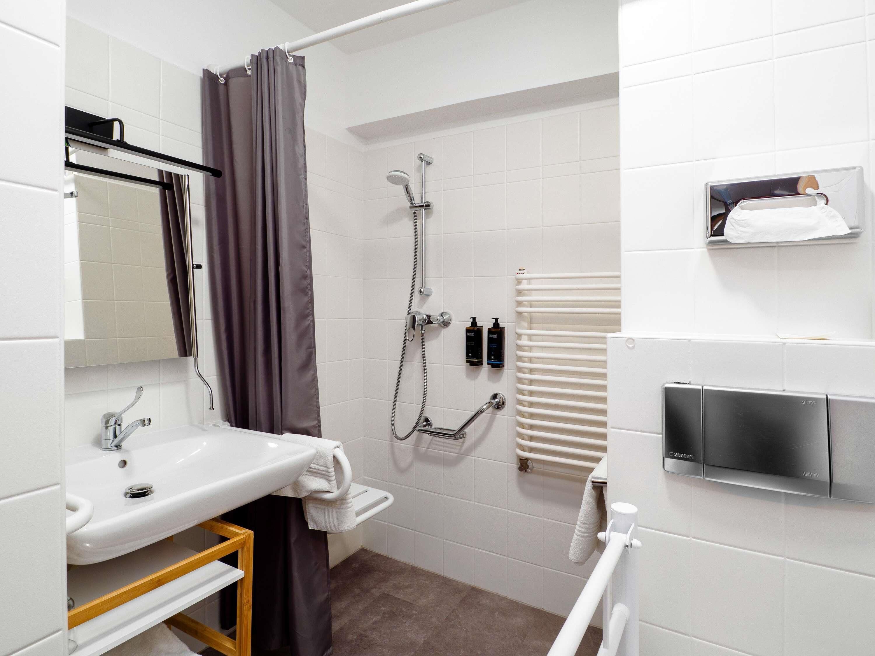 A modern bathroom with a white sink, shower, and toilet.
