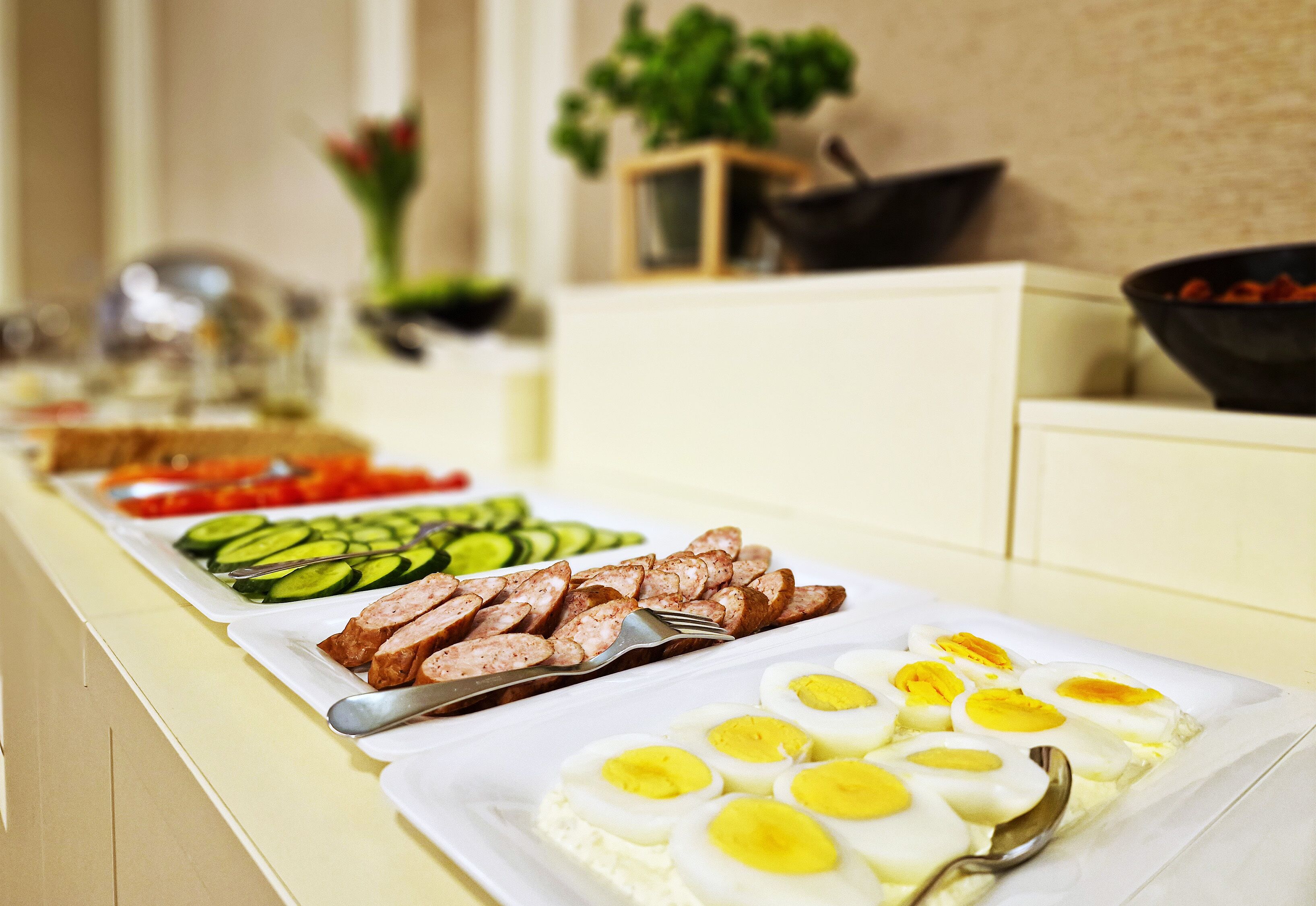 A buffet with sliced meats, vegetables, and hard-boiled eggs.