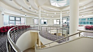Un interior espacioso con varios niveles, ventanas amplias y una escalera central.