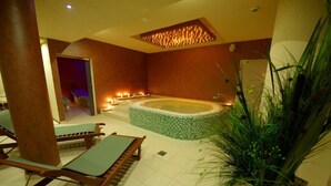 Un cuarto de spa con hidromasaje, sillones de descanso y velas.