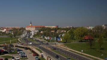 A cityscape with a prominent building with a tower, multiple roads, and a parking area.