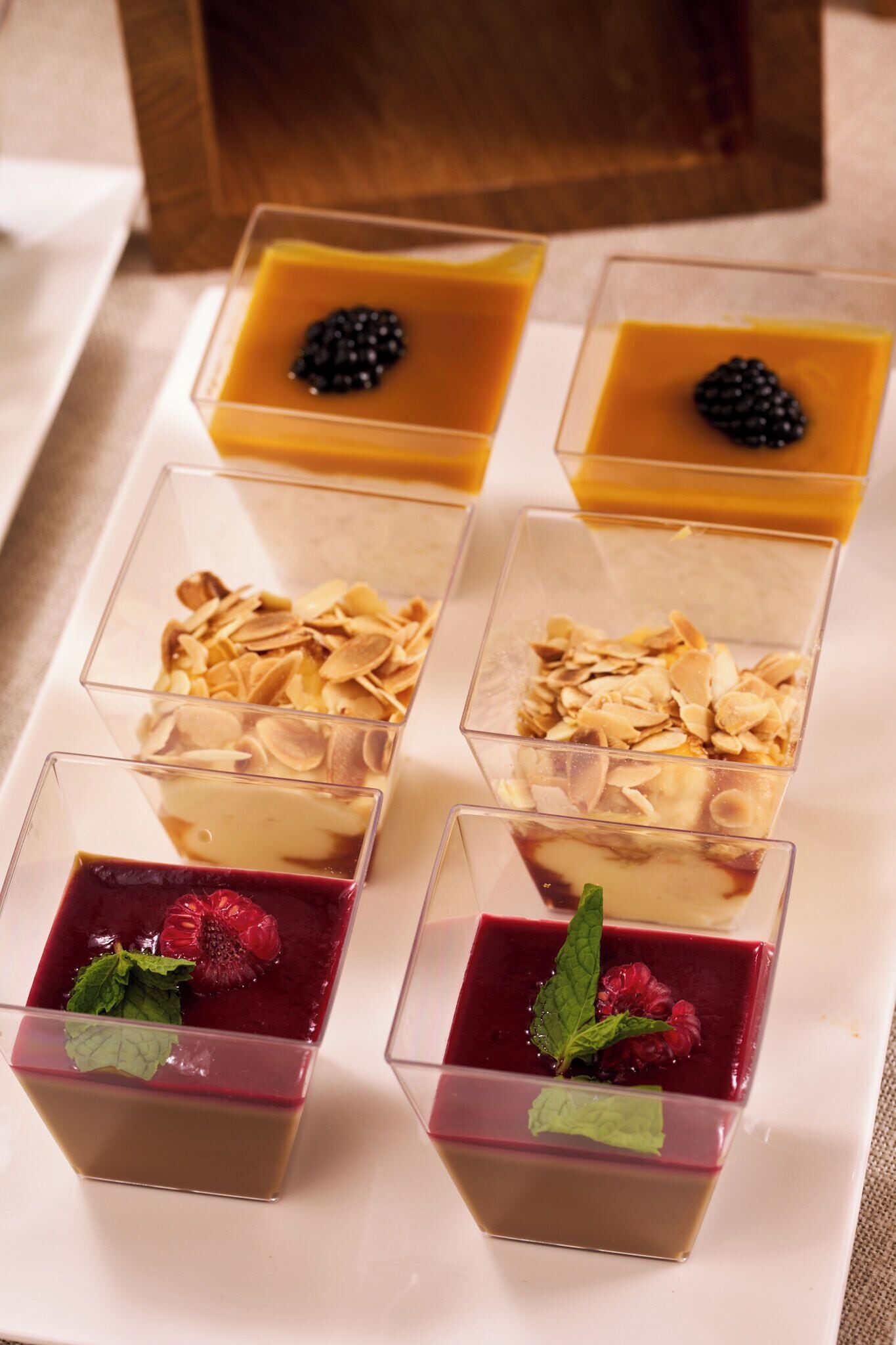Four square dessert glasses with different toppings.