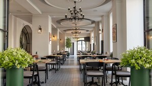 A spacious restaurant with high ceilings, chandeliers, and potted plants. - Hotel Cristal (Bialystok)