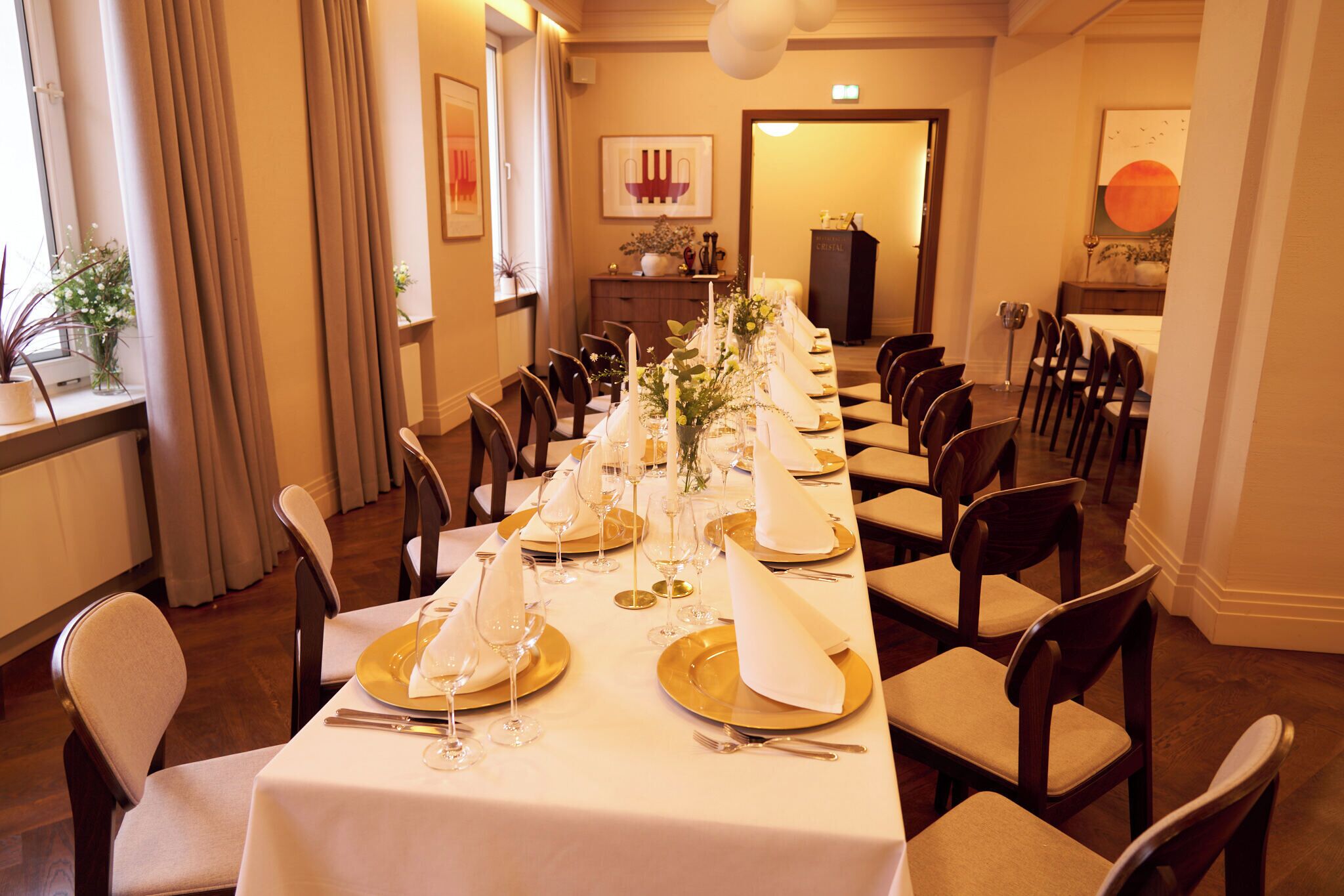 A dining room with a long table set for a meal, chairs, and a decorative centerpiece.