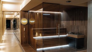 A modern hotel lobby with a wooden reception desk, a glass partition, and a sauna sign. - Hotel Cristal (Bialystok)