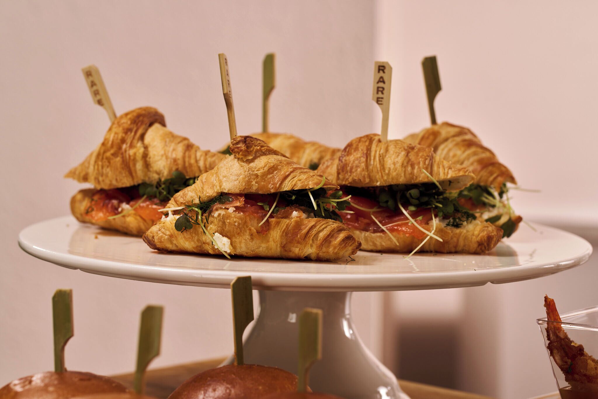 A plate with croissant sandwiches, each with a toothpick labeled 'RARE'.