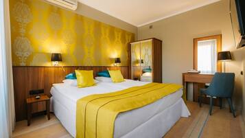 A hotel room with a large bed, bedside tables, a desk, and a chair.