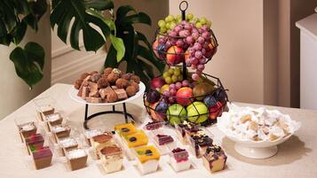 A dessert table with various sweets and fruits.